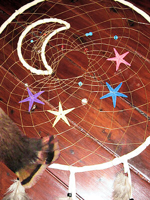 detail of sun, moon, and stars dream catcher web and feathers